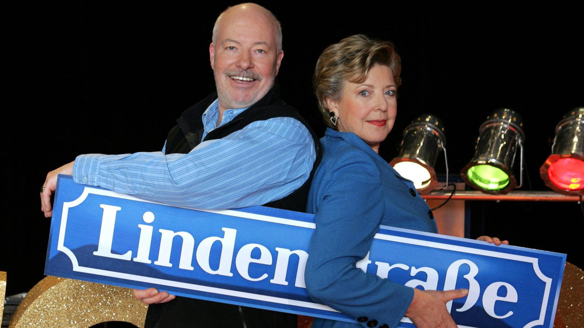Die „Lindenstraßen“-Schauspieler Bill Mockridge und Marie-Luise Marjan halten ein Schild mit dem Titel der ARD-Kultserie.