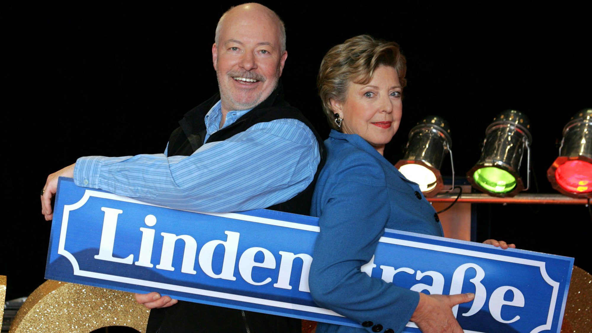 Die „Lindenstraßen“-Schauspieler Bill Mockridge und Marie-Luise Marjan halten ein Schild mit dem Titel der ARD-Kultserie.