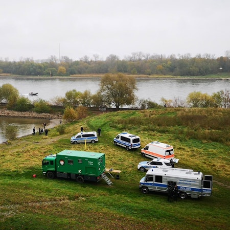 Autos der Polizei auf einer Wiese am Ufer am Niehler Hafen