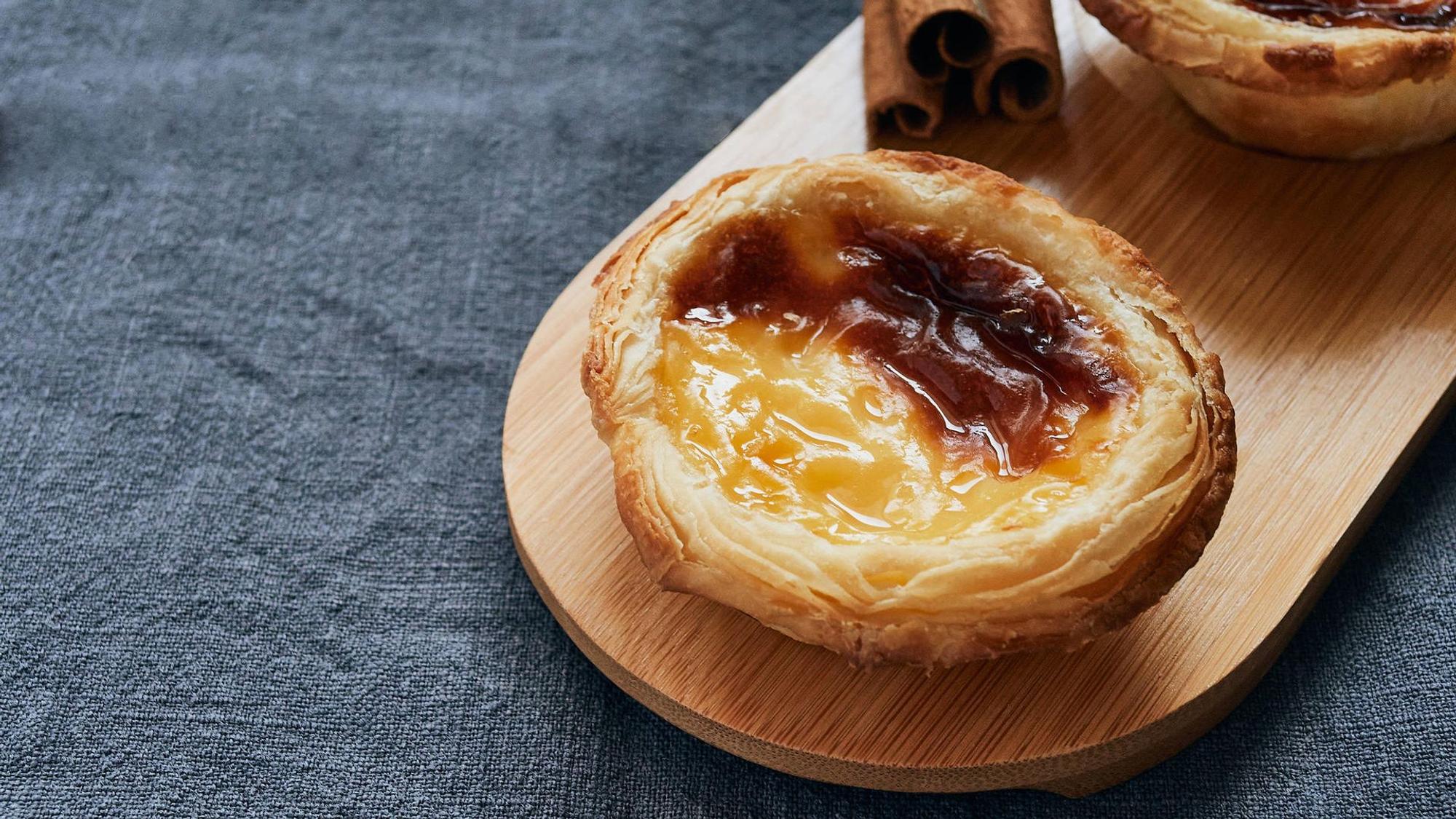 Der portugiesische Nachtisch Pasteis de Nata auf einem Brettchen serviert.