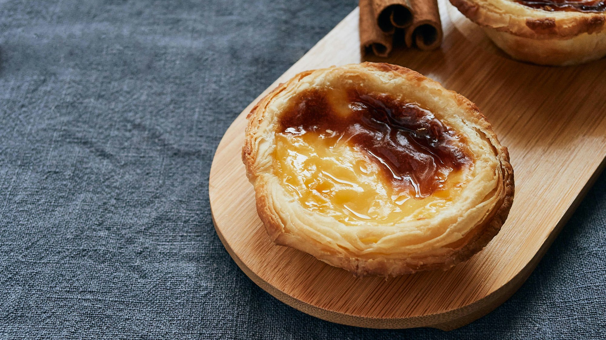 Der portugiesische Nachtisch Pasteis de Nata auf einem Brettchen serviert.