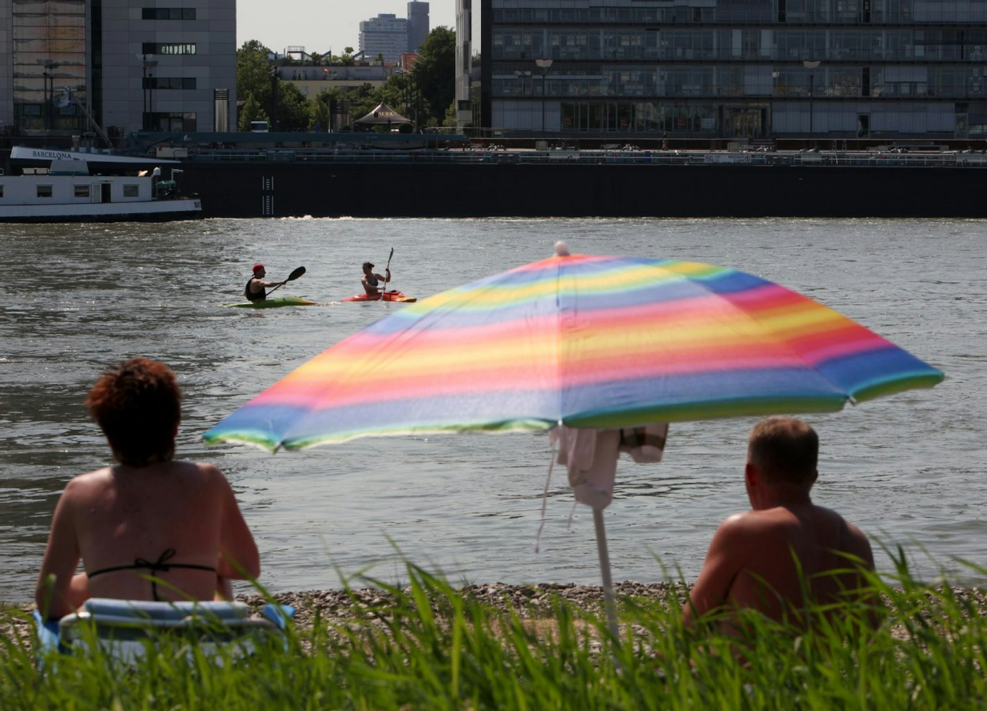 Ein Paar guckt beim Sonnen auf den Rhein in Köln.