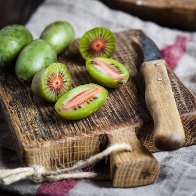 Minikiwis liegen angeschnitten auf einem Brettchen