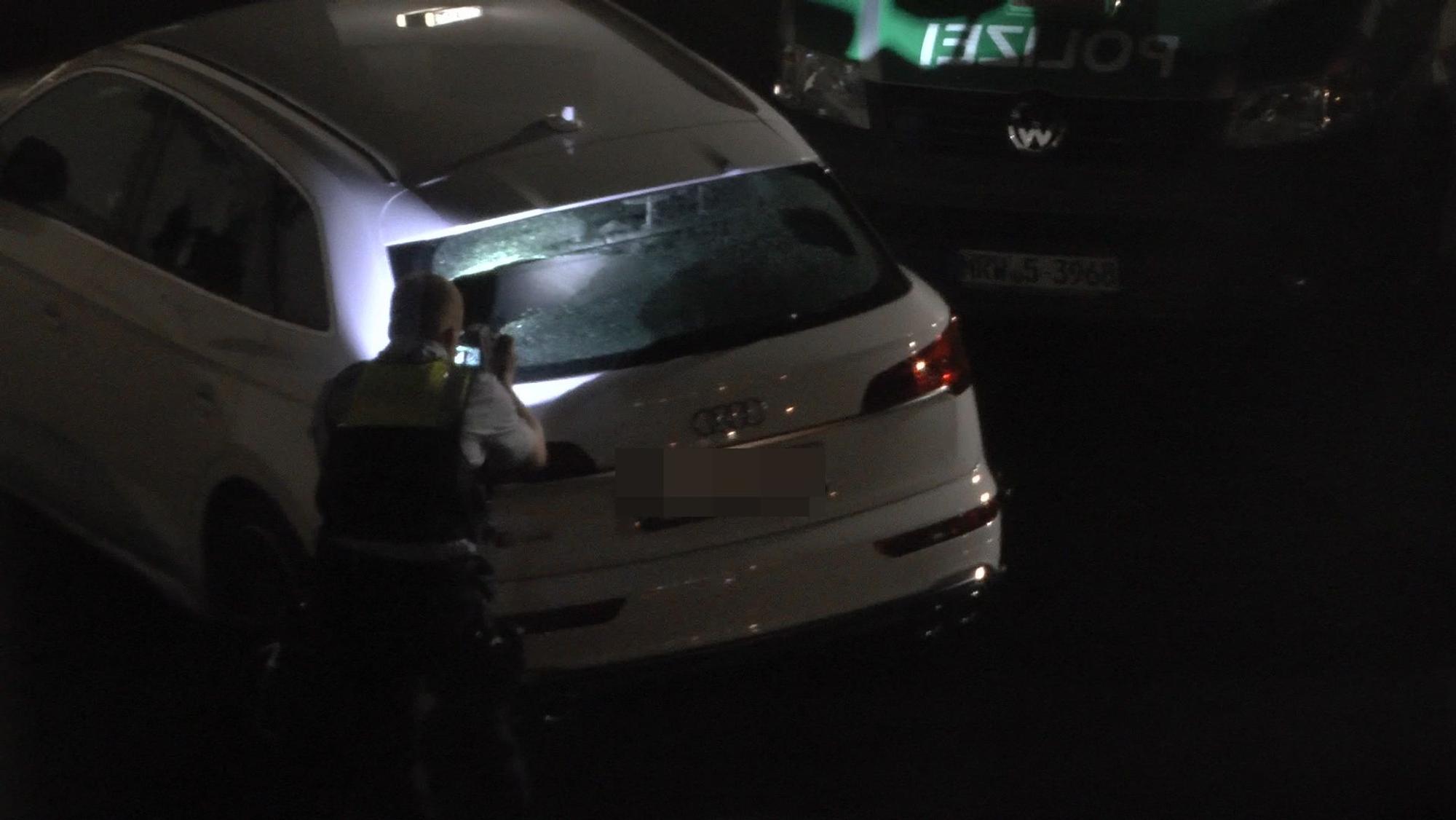 Ein Polizist sammelt Spuren an einem Fahrzeug.