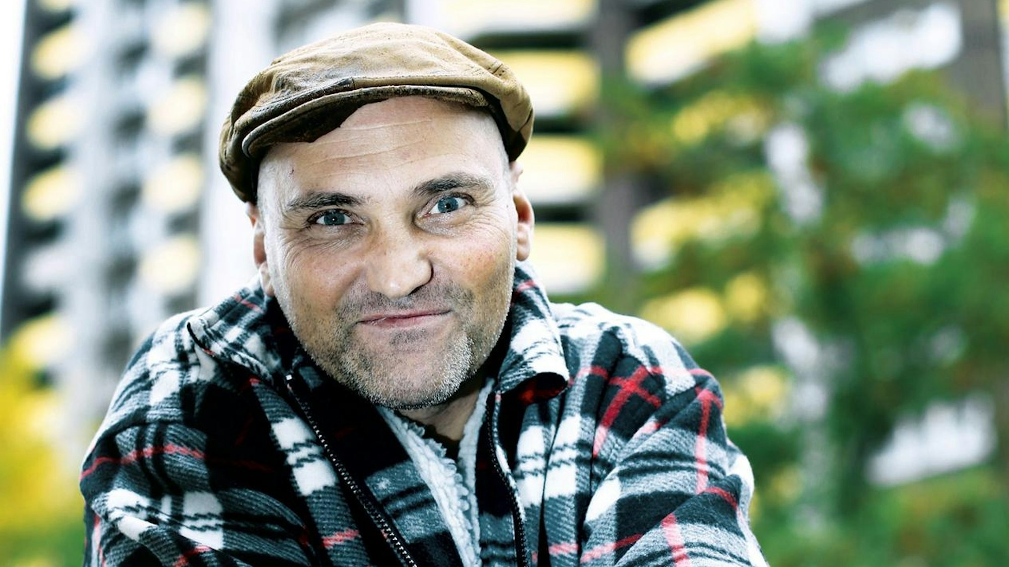 Franco Clemens lächelt vor einer Hochhausfassade in die Kamera.