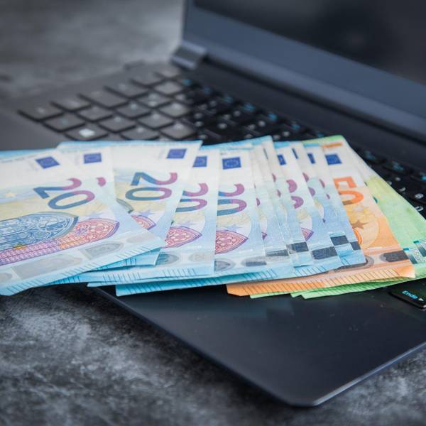 Verschiedene Euro-Scheine liegen auf einem Laptop.