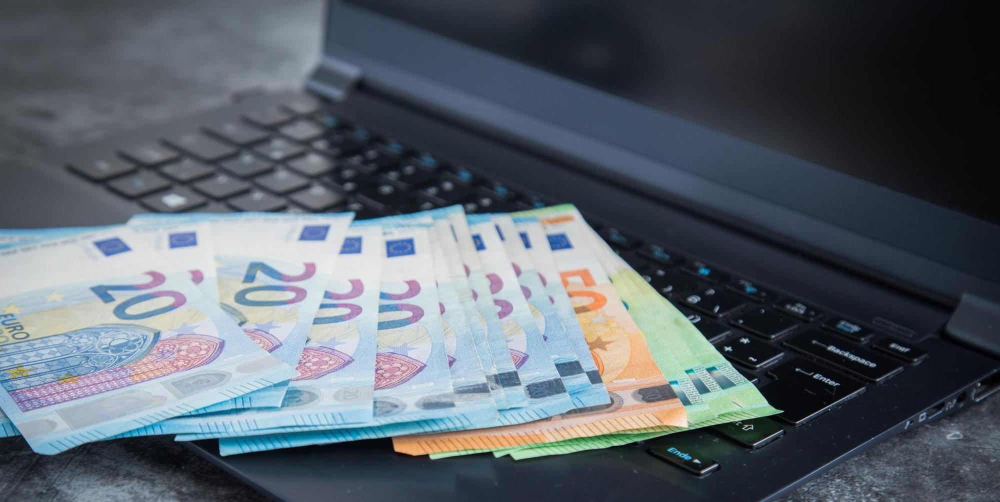 Verschiedene Euro-Scheine liegen auf einem Laptop.