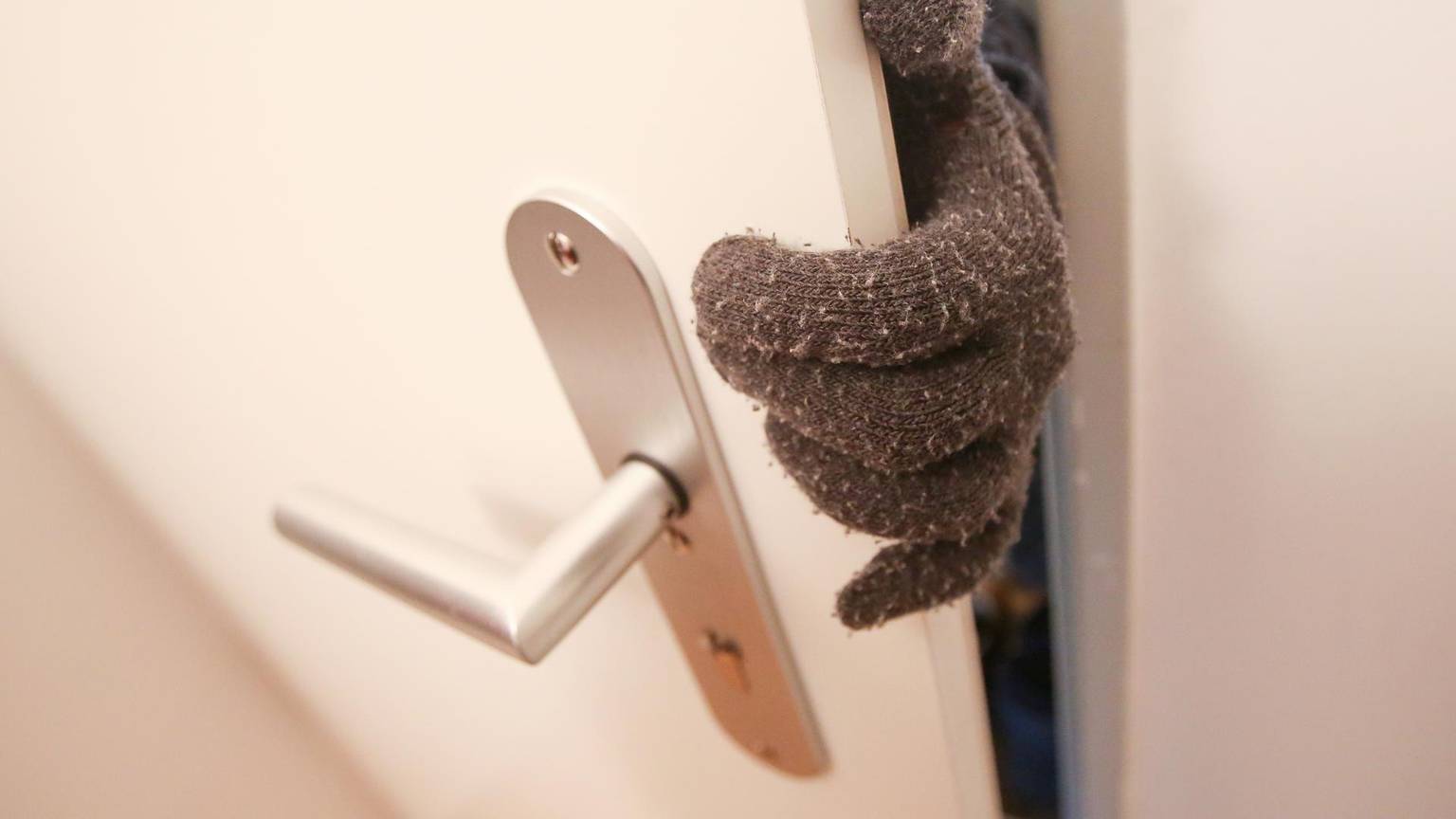 Dieb Einbrecher an Tür nur Handschuh zu sehen