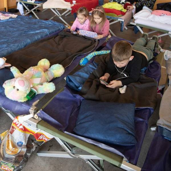 Kinder liegen mit ihren Stofftieren auf einem Matratzenlager in einer Flüchtlingtsunterkunft.