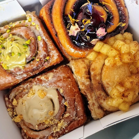 Lecker angerichtete und verzierte Zimtschnecken liegen in einer To-Go-Box.