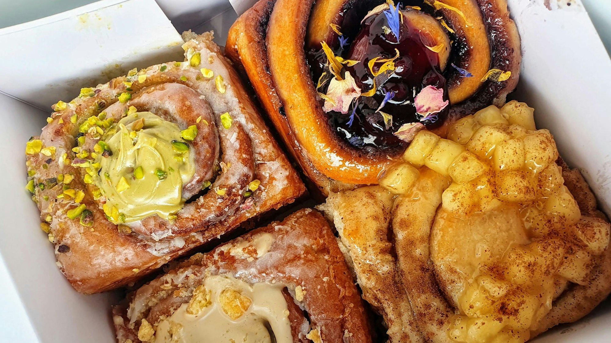 Lecker angerichtete und verzierte Zimtschnecken liegen in einer To-Go-Box