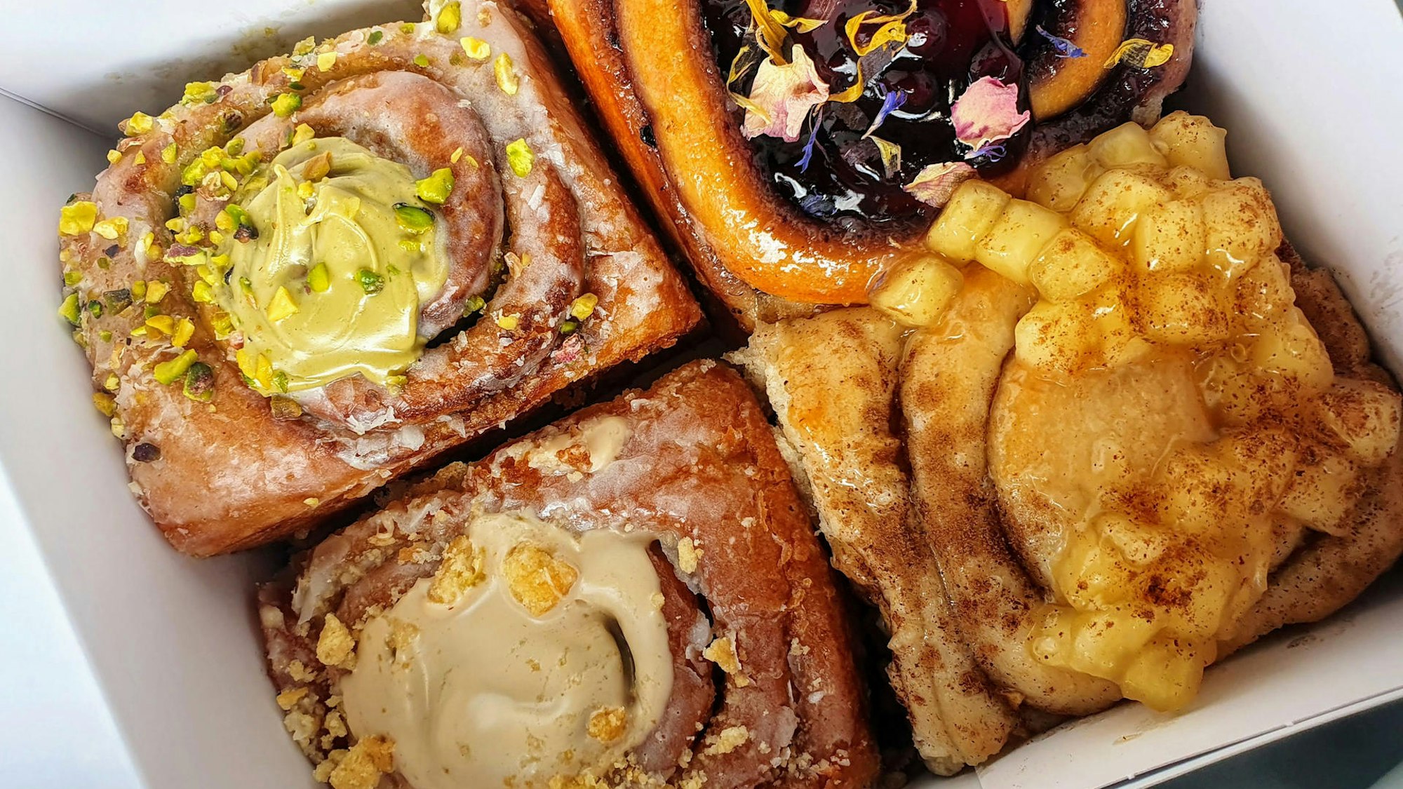 Lecker angerichtete und verzierte Zimtschnecken liegen in einer To-Go-Box.