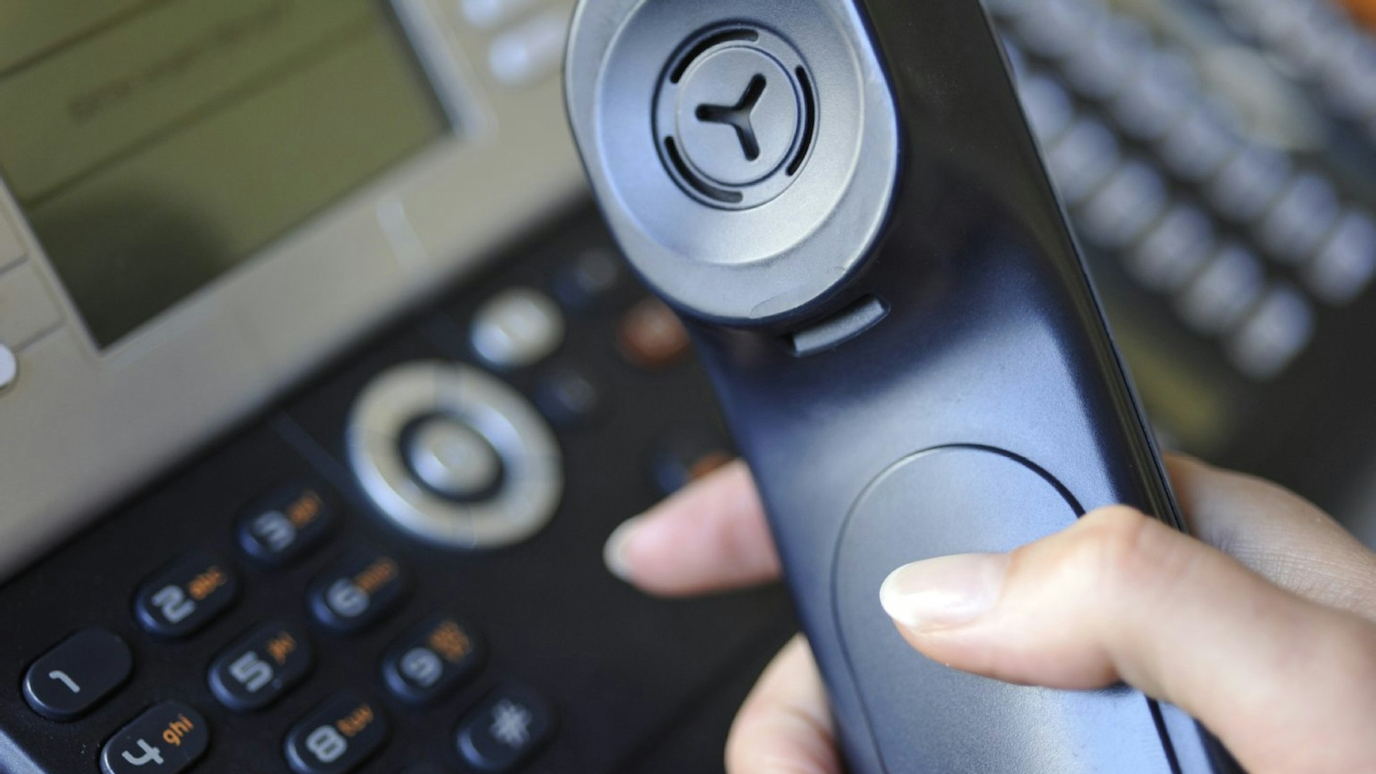 Ein Telefon und ein Telefonhörer in einer Hand.